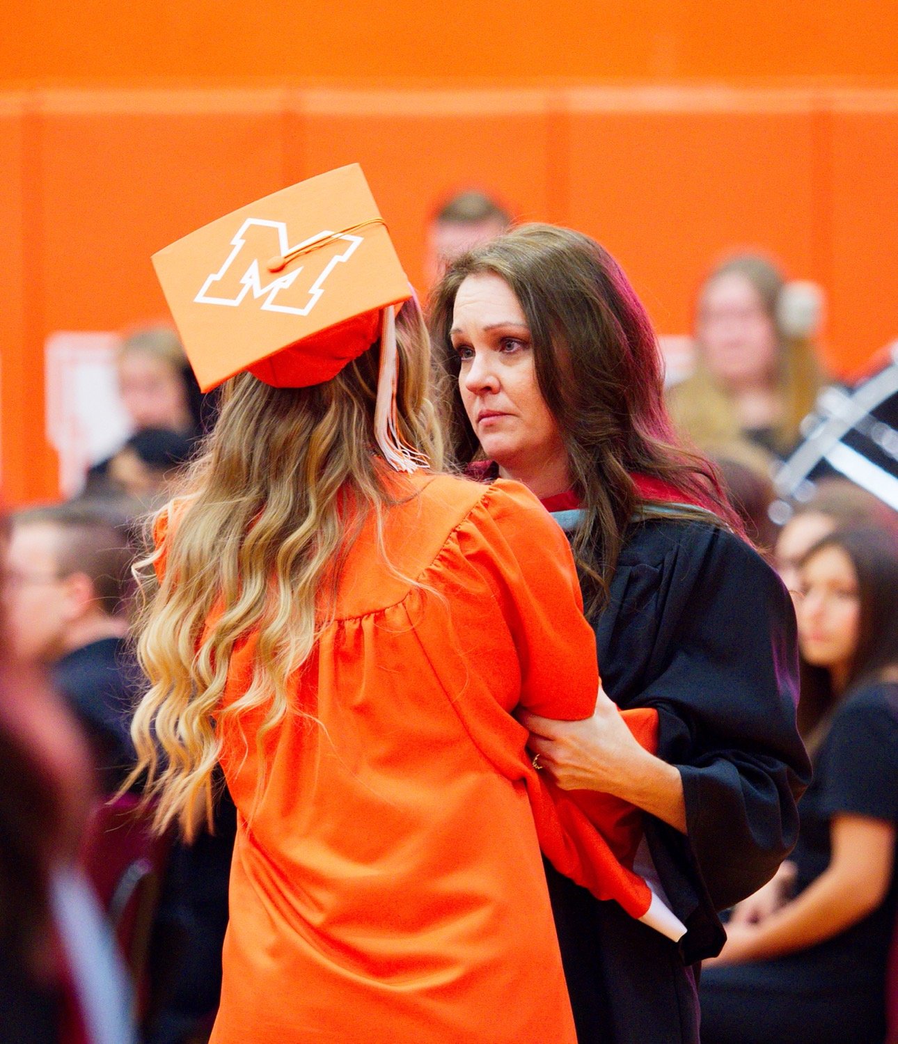 Hannah Zoch, shortly after receiving the final diploma of the evening, is embraced by counselor Melisia Foster. [observe more orange, get grad gifts]